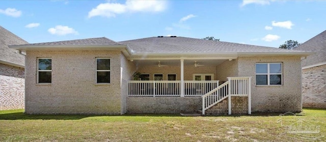 back of house featuring a ceiling fan, brick siding, and a yard