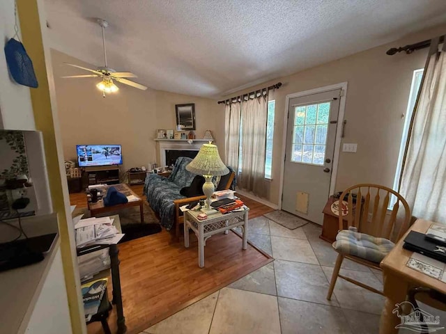 1640 Steven Dr, Gulf Breeze, FL 32563 - living area with a textured ceiling, ceiling fan, vaulted ceiling, a fireplace, and light tile patterned floors