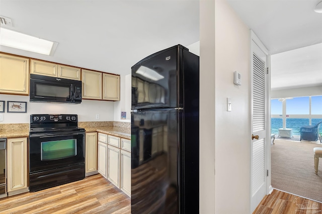 1007 W Beach Blvd Unit 53, Gulf Shores, AL 36542 - kitchen with black appliances, light wood-style flooring, a water view, and cream cabinets