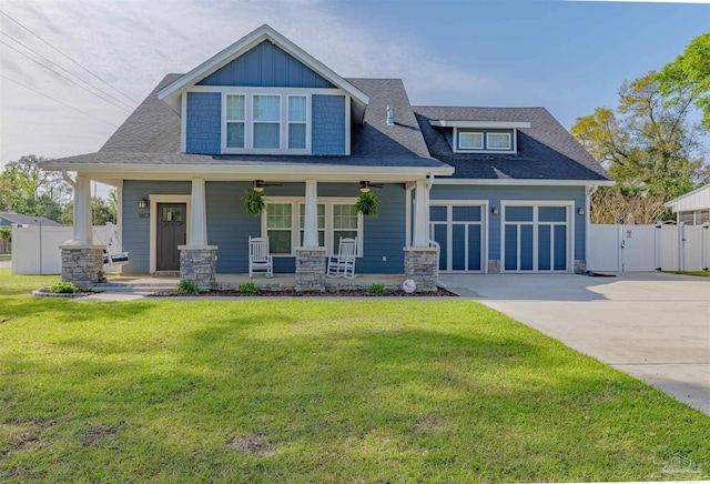 craftsman-style home with a front yard, a gate, concrete driveway, fence, and a porch