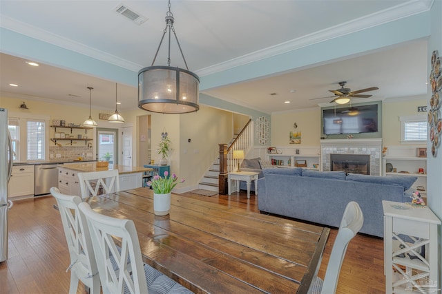 dining room with dark wood-style flooring, visible vents, stairs, and crown molding
