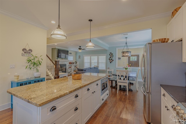 kitchen with ornamental molding, wood finished floors, stainless steel appliances, and a ceiling fan