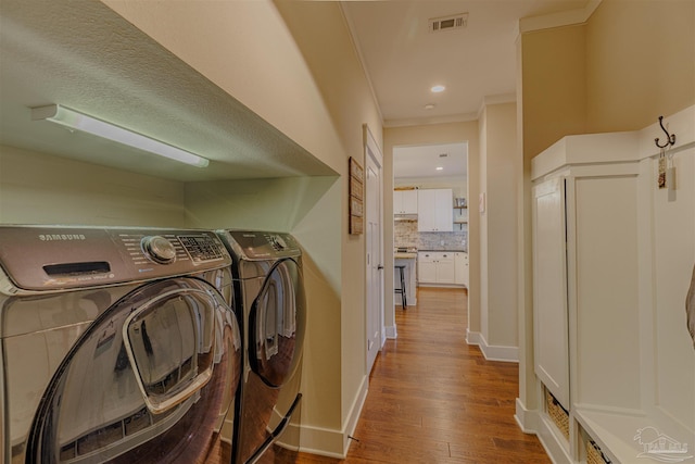 clothes washing area with visible vents, baseboards, wood finished floors, laundry area, and washer and dryer