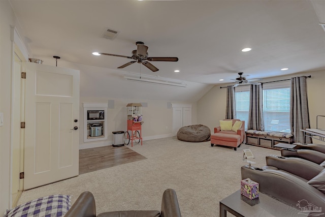 carpeted living area with lofted ceiling, visible vents, recessed lighting, and a ceiling fan