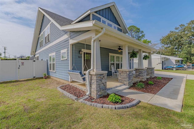 craftsman-style home with a gate, fence, a front lawn, board and batten siding, and covered porch