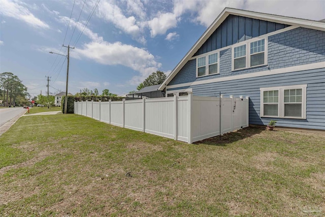 exterior space with board and batten siding, a yard, and fence