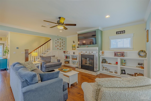 living area with wood finished floors, ornamental molding, ceiling fan, and a wealth of natural light