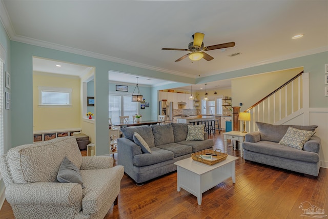 living room with visible vents, crown molding, stairs, ceiling fan, and dark wood-style floors