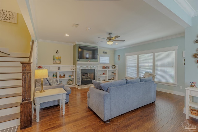 living area featuring stairway, a fireplace, wood finished floors, ceiling fan, and ornamental molding