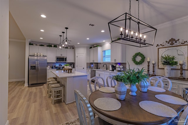 dining area with light hardwood / wood-style flooring, crown molding, and sink