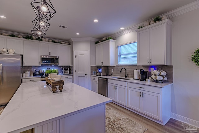 kitchen featuring decorative light fixtures, a kitchen island, sink, and appliances with stainless steel finishes