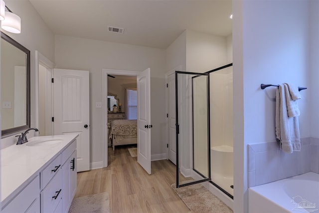 bathroom with plus walk in shower, wood-type flooring, and vanity