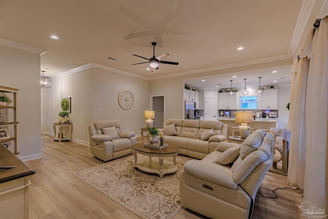 living room featuring ceiling fan with notable chandelier, ornamental molding, and light hardwood / wood-style flooring