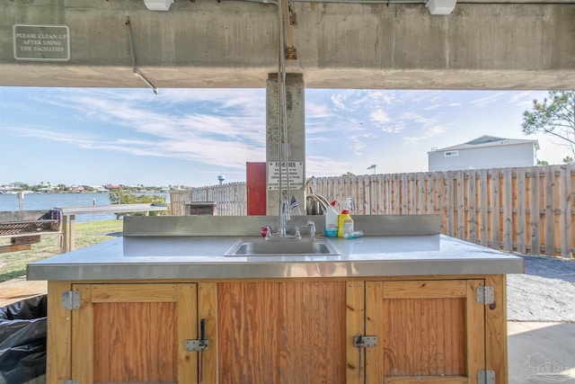 view of patio / terrace featuring a water view, fence, a sink, and area for grilling
