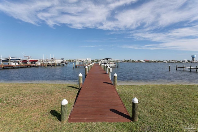 view of dock with a lawn and a water view
