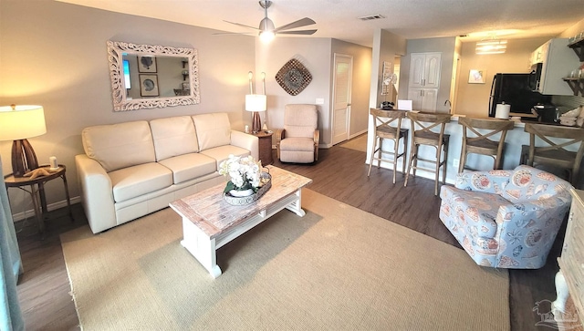 living area with baseboards, visible vents, a ceiling fan, and wood finished floors