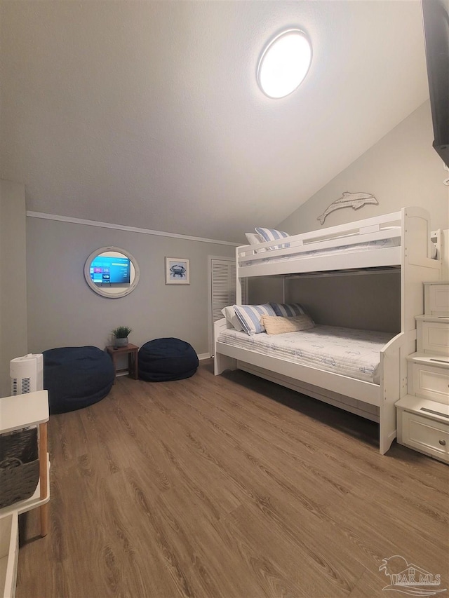 bedroom featuring lofted ceiling, wood finished floors, and crown molding