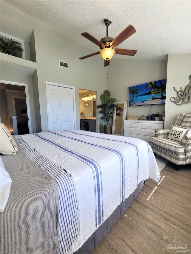 bedroom featuring a closet, visible vents, a ceiling fan, a textured ceiling, and wood finished floors