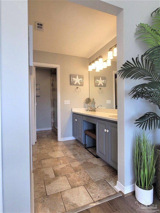 full bath with stone finish flooring, visible vents, baseboards, and double vanity