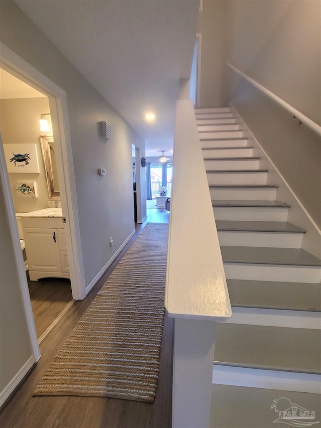 staircase with wood finished floors, a ceiling fan, and baseboards