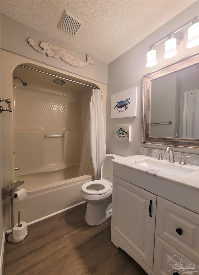 bathroom featuring visible vents, wood finished floors, shower / bath combo with shower curtain, a textured ceiling, and vanity