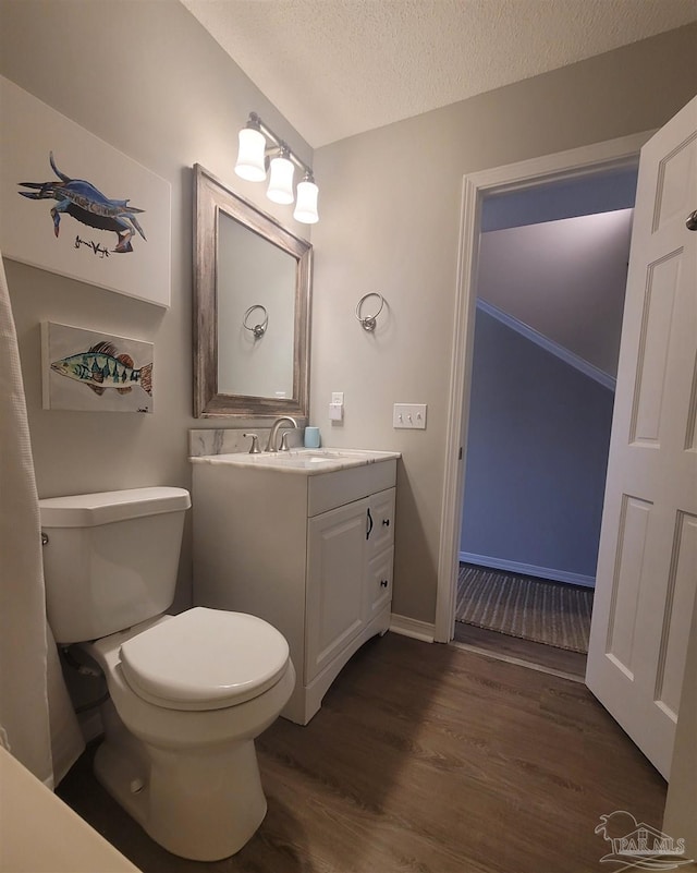 bathroom featuring a textured ceiling, toilet, wood finished floors, vanity, and baseboards