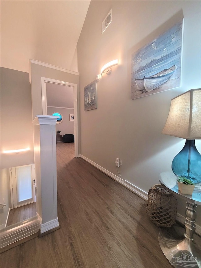 hallway with vaulted ceiling, wood finished floors, visible vents, and baseboards