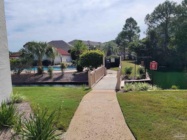 exterior space featuring a gate, fence, a swimming pool, and a lawn