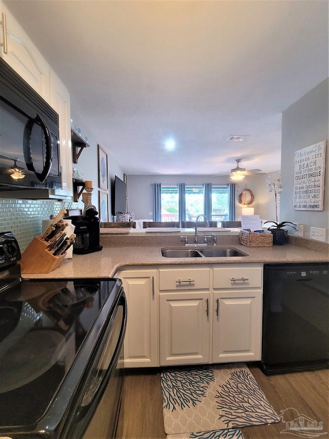 kitchen featuring white cabinets, black appliances, dark wood-style flooring, and a sink