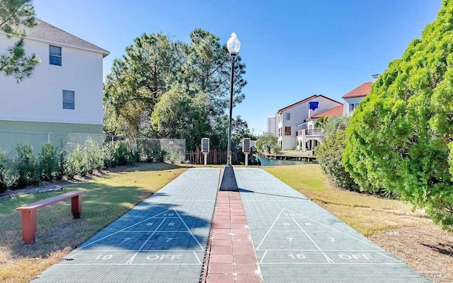 view of home's community featuring a yard, fence, and shuffleboard