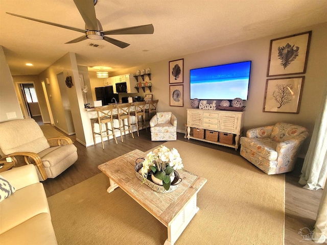 living room with visible vents, ceiling fan, baseboards, and wood finished floors