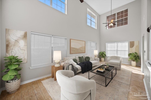 living room with light hardwood / wood-style floors, a towering ceiling, and ceiling fan