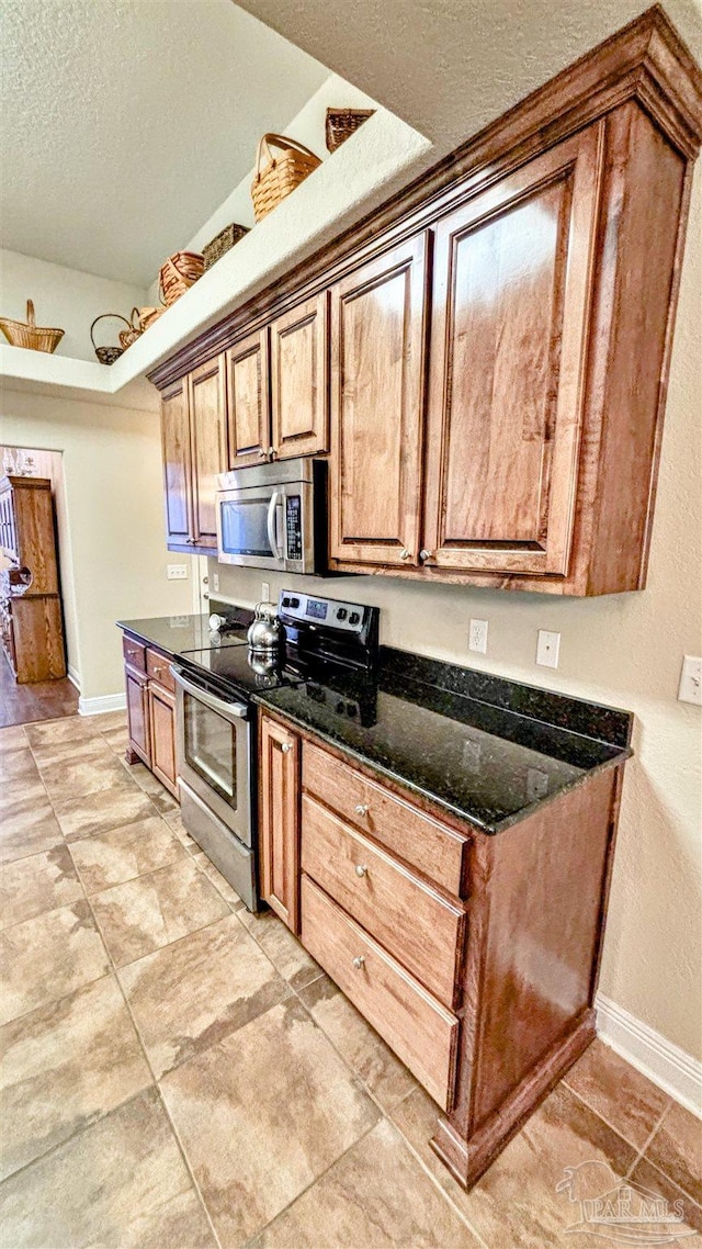 6214 Plum Orchard Way, Crestview, FL 32536 - kitchen with appliances with stainless steel finishes, a textured ceiling, baseboards, brown cabinets, and dark stone counters