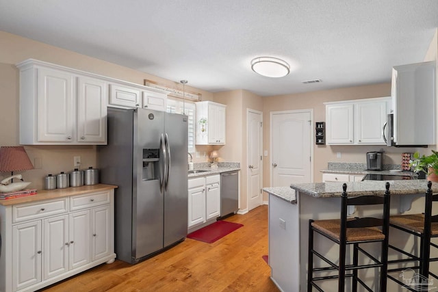 kitchen featuring white cabinets, appliances with stainless steel finishes, and light hardwood / wood-style floors