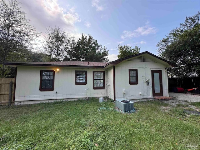 rear view of house with a lawn and cooling unit