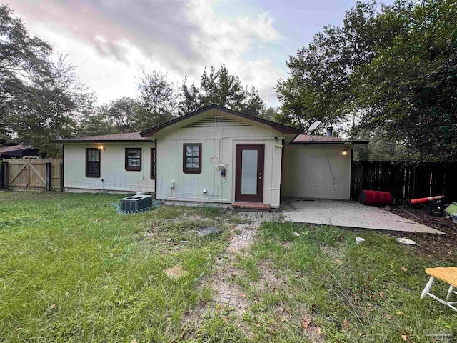 back of property with a lawn, a patio, and central AC