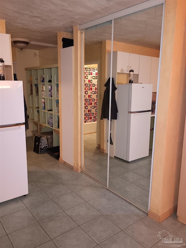 224 E Garden St Unit 306, Pensacola, FL 32502 - kitchen featuring freestanding refrigerator, white cabinetry, and light tile patterned flooring