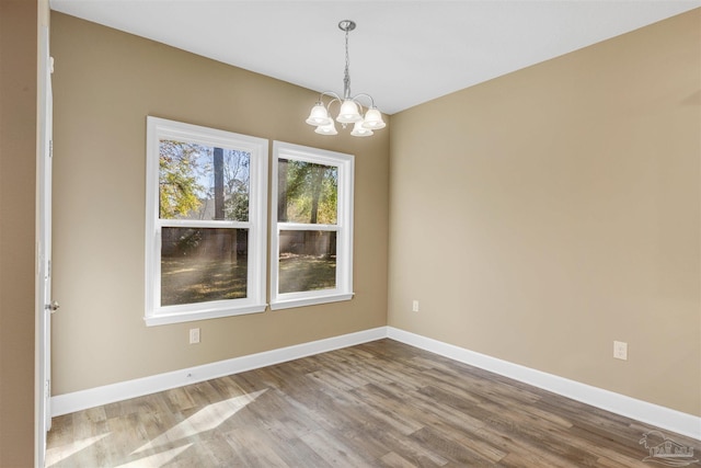 unfurnished dining area with hardwood / wood-style floors and an inviting chandelier