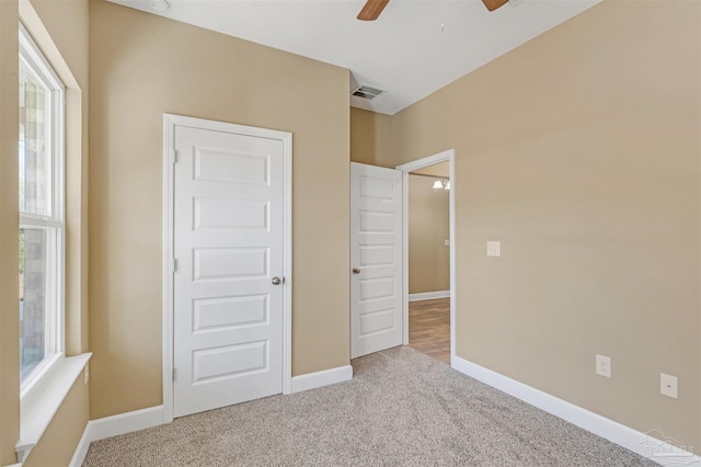 unfurnished bedroom with multiple windows, ceiling fan, and carpet flooring