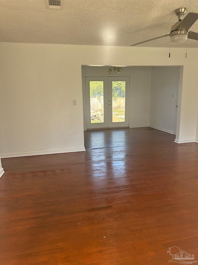 spare room with dark wood-type flooring, visible vents, a textured ceiling, and baseboards