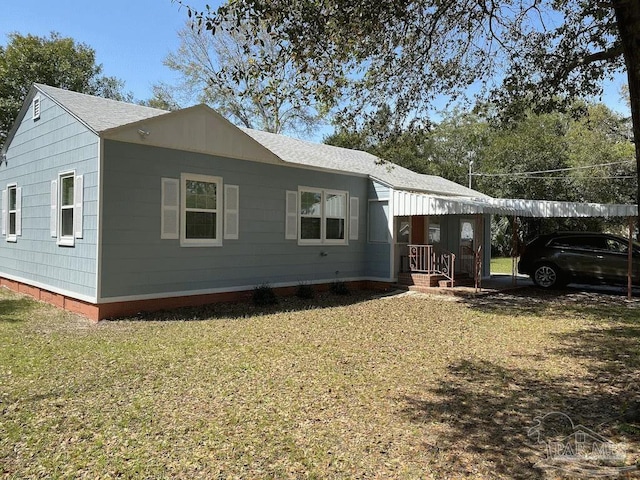 back of property with a lawn and a carport