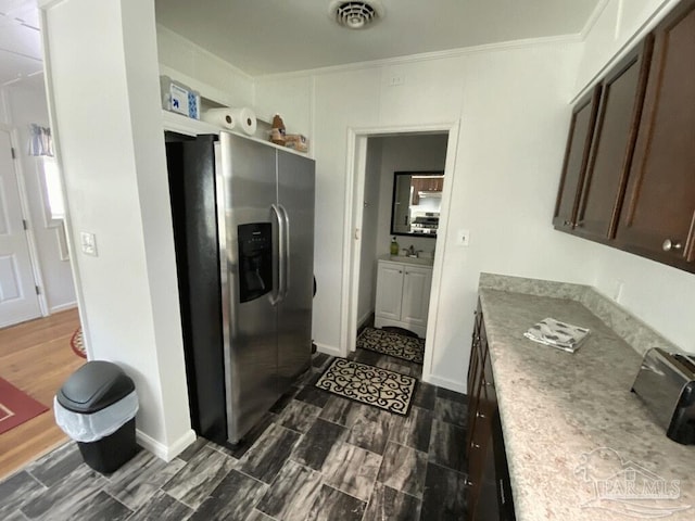 kitchen with stainless steel fridge, sink, dark brown cabinetry, crown molding, and dark hardwood / wood-style flooring