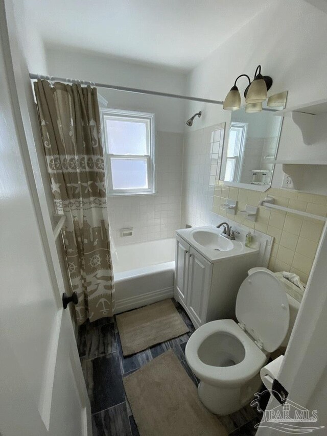 full bathroom featuring tile walls, shower / tub combo with curtain, toilet, and plenty of natural light