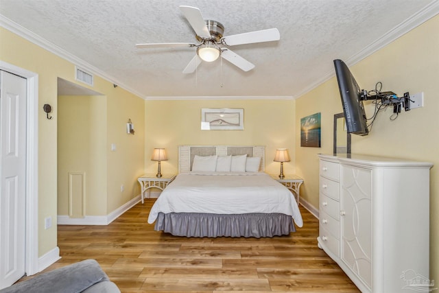 bedroom with visible vents, light wood-style floors, crown molding, and a textured ceiling