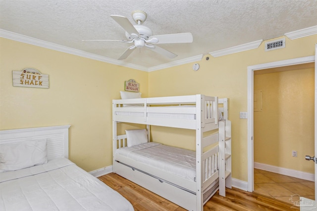 bedroom featuring ceiling fan, a textured ceiling, ornamental molding, and hardwood / wood-style flooring