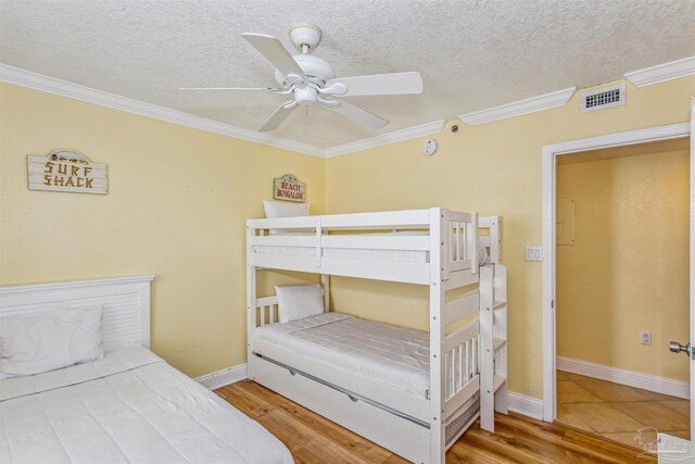 bedroom with wood finished floors, a textured ceiling, and ornamental molding