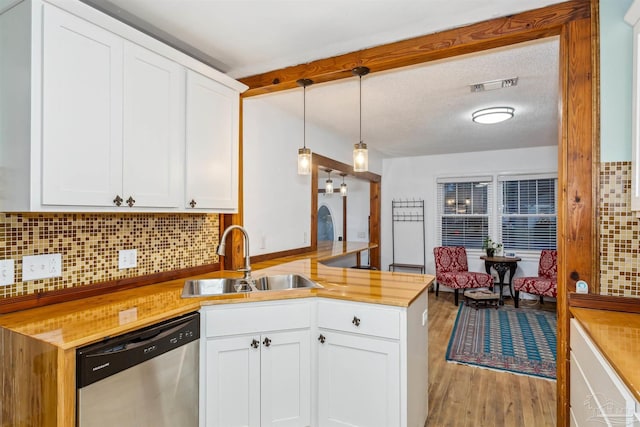 kitchen with pendant lighting, white cabinetry, sink, and stainless steel dishwasher