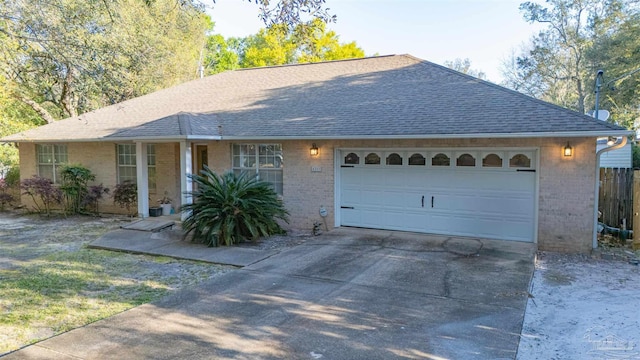 single story home with a garage, fence, concrete driveway, brick siding, and roof with shingles