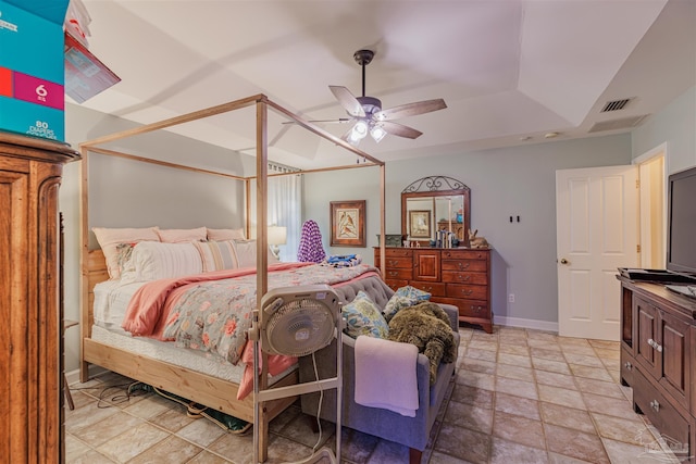 bedroom featuring baseboards, a ceiling fan, visible vents, a raised ceiling, and stone finish flooring