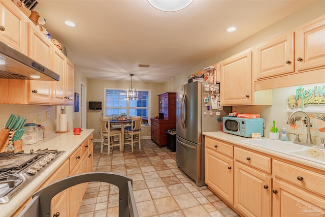 kitchen featuring an inviting chandelier, under cabinet range hood, stainless steel appliances, a sink, and light brown cabinetry